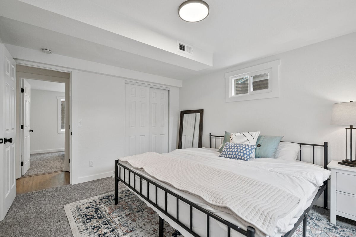 Cozy bedroom remodel by Triple Crown Contractors in Raleigh, NC, with a minimalist design, white walls, and a modern black metal bed frame