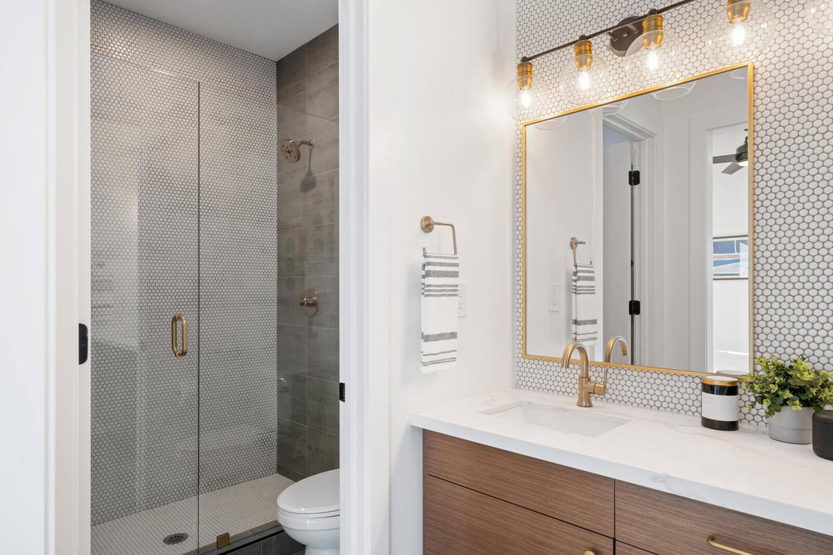 Modern bathroom remodel with stylish penny tile and gold accents by Triple Crown Contractors in Apex, NC