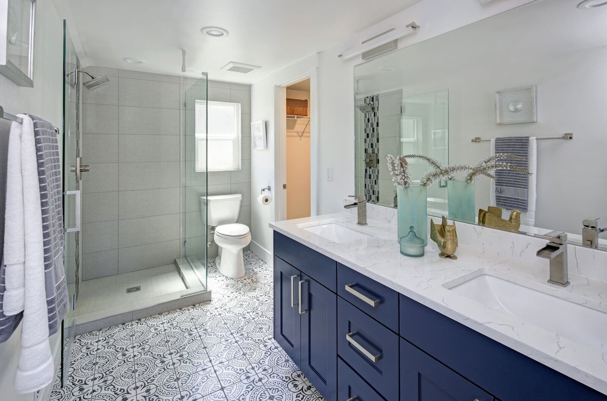Stylish bathroom remodel featuring a bold blue double vanity and a walk-in glass shower in Durham, NC