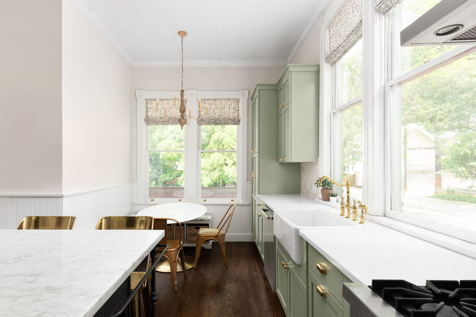 Bright and airy kitchen remodel by Triple Crown Contractors in Raleigh, NC, with sage green cabinets, marble countertops, and large windows
