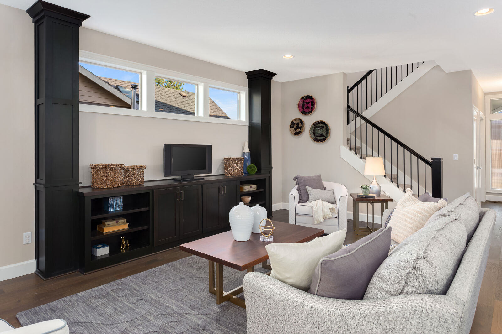 Modern living room with black cabinetry and an open-concept staircase in a whole home remodel by Triple Crown Contractors in Apex, NC